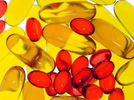 Transparent yellow and red capsules closeup background.