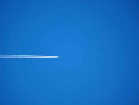 airplane in the blue sky with contrail, closeup of photo.の写真素材