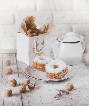 Muffins, nuts and teapot on white tableの写真素材