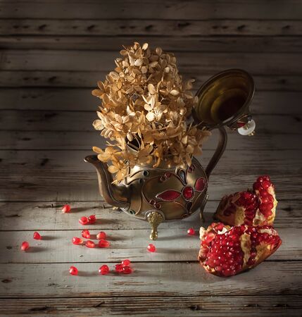 Oriental teapot with flower and pomegranate on an old white cracked wooden tableの写真素材