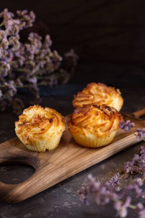 Three curd cakes on a wooden tray. In the background many small flowersの写真素材