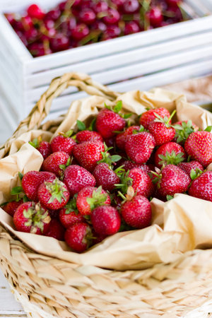 Strawberries in a wicker basket on a wooden table.の写真素材