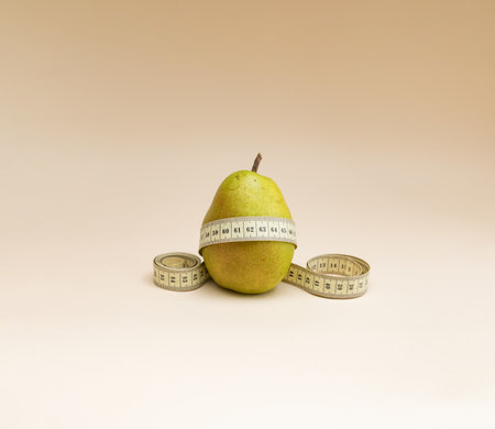 Pear with a measuring tape on a beige background. Diet conceptの写真素材