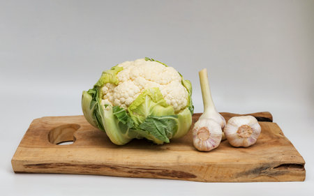 Cauliflower and garlic on a chopping board on a white backgroundの写真素材