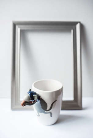 white ceramic mug with a picture of a mouse stands on a table with a gray on a white backgroundの写真素材