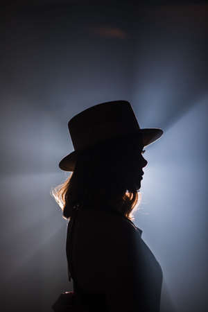 silhouette of a beautiful girl in a hat in backlight side view close-upの写真素材