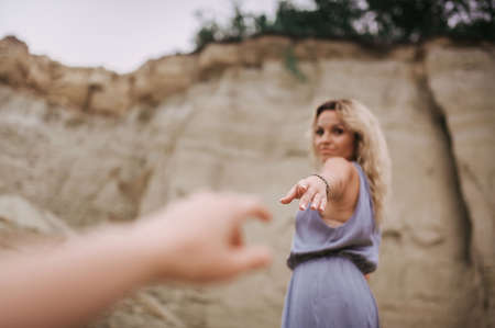 blonde girl in a gray dress extends her hand to the cameraman behind the scenes in the style ofの写真素材