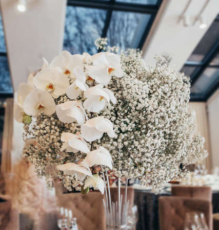 bouquet decoration with white flowers on wedding table decor, close-up front view on restaurant interior backgroundの写真素材