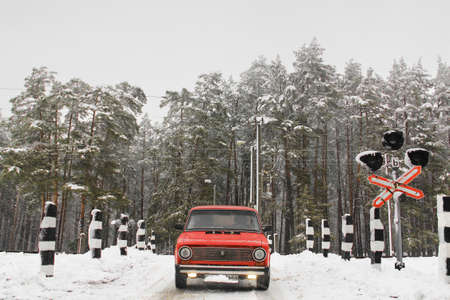 Chernihiv, Ukraine - January 20, 2020: Old red VAZ 21011 car in the winter forest against the background of a railway crossingのeditorial素材