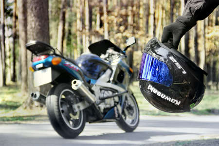 Chernihiv, Ukraine - April 7, 2020: Helmet in hand on the background of a Kawasaki motorcycle in the forestのeditorial素材