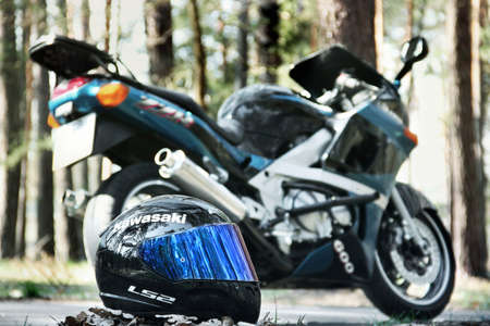Chernihiv, Ukraine - April 7, 2020: A motorcycle helmet on the background of a Kawasaki motorcycle in the forestのeditorial素材
