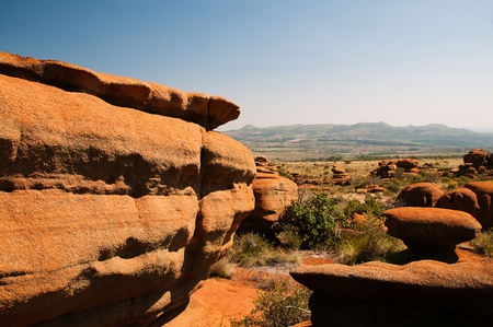 A group of fantastically nature shaped yellow rocks in the SA Magaliesberg plateau on a sunny day with blue sky and hills in the backgroundの写真素材