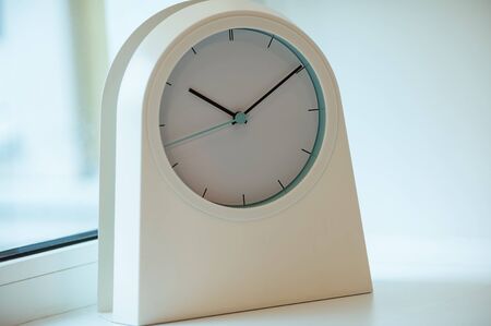 A closeup of a white modern clock on a window sillの写真素材