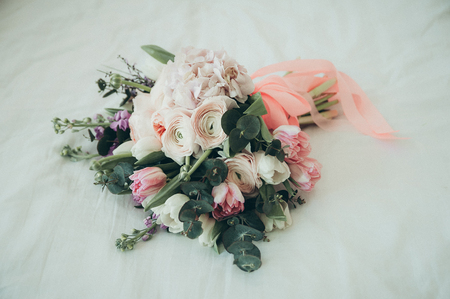 A closeup view of a beautiful trendy bridal bouquet on a white bedの写真素材