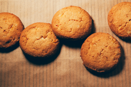Closeup top view of round crunchy sweet biscuits with candied fruit, on mat baking paper background