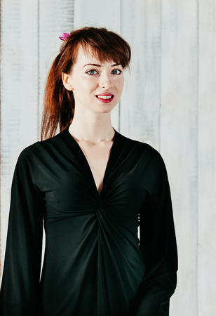 a portrait of pretty smiling girl in black dress, with light backgroundの写真素材