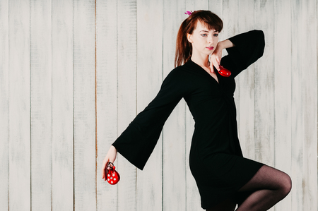 a young elegant girl in black dress, dancing flamenco with red castanets, light backgroundの写真素材
