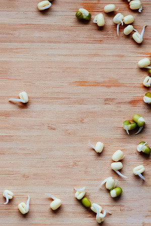 Mung beans sprouts scattered on a wooden table, top view, vertical image, copy spaceの写真素材
