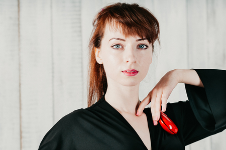 closeup view of a pretty blue-eyed woman in black dress, dancing flamenco with red castanets, light backgroundの写真素材