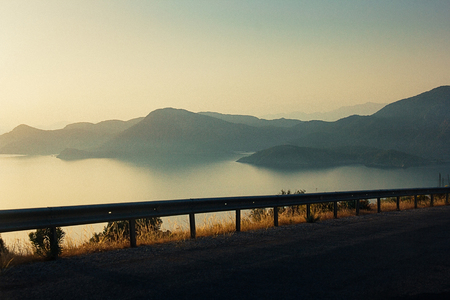 Beautiful view on sea and sunset over the distant hills from a serpentine mountain road (blurred motion). Film grain effect. Oludeniz bay near Fethiye, Turkeyの写真素材