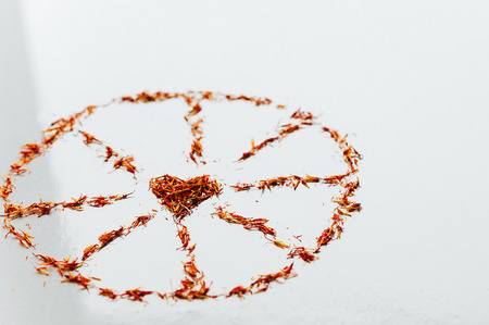 Selective focus Red Saffron in shape of circle with heart on white background. Delicate flower threads. Top view of natural healthy spice. Copy space for text and designの写真素材