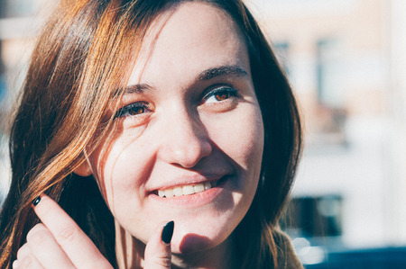 Beauty portrait of chestnut heard young woman enjoying sunny day, natural make-up. Street fashion, genuine smile. Pretty look, freckled skin. Close up view. Emotion, lifestyle conceptの写真素材