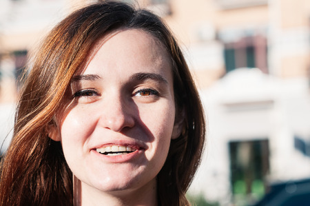 Freckled brunette young woman enjoying sunny day, natural make-up. Street fashion, genuine smile. Pretty look, clean perfect skin. Close up view. Emotion, mimic, state of mind conceptの写真素材