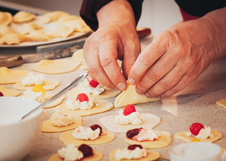 Chef hands preparing cheese and cherry dumplings, old person hands in process of cooking, side viewの写真素材