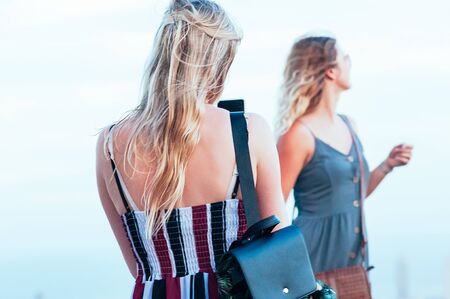 Beautiful female friends, enjoying posing and taking candid photos. Fashion look. Wind through long...
