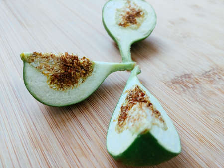 Unripe fresh green fig cut into three slices on the wooden bamboo board close up viewの写真素材