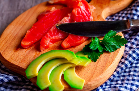 Sliced avocado and salmon on a wooden Board.Knife. Blue napkinの写真素材