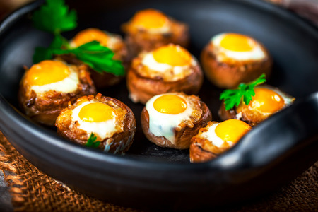 Mushrooms with quail eggs. Mushrooms on black pan. Selective focusの写真素材