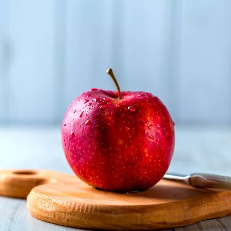 Ripe red Apple lying on a wooden Board. Apple in the water droplets. Knif on a background. Healthy food conceptの写真素材