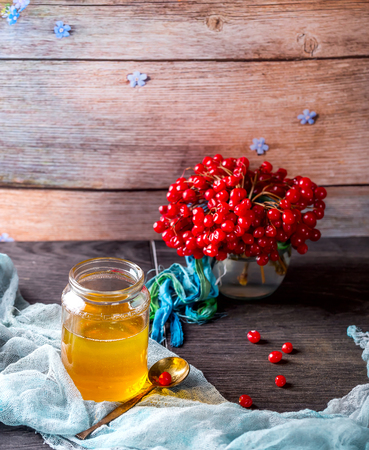 Jar of honey and the branches of viburnum on the table. Honey and viburnum on blue napkin . Wooden background. The concept of healthy food. Selective focusの写真素材