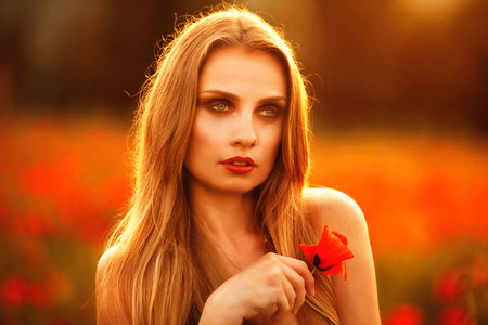 Beautiful woman in a poppy field with flowers.の写真素材