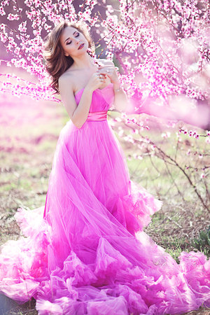 Adorable girl in blooming peach garden on sunny spring dayの写真素材