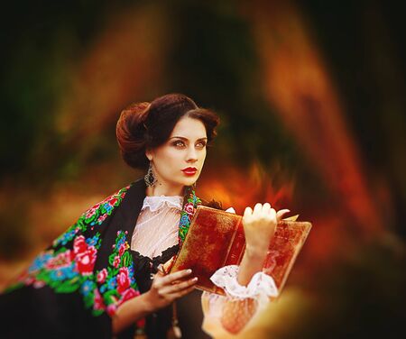 beautiful woman in vintage dress walking in autumn park.の写真素材