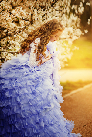 Adorable little girl in blooming cherry tree garden on beautiful spring day.の写真素材