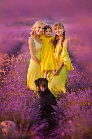 family. care for the younger ones. sisters with a doll in their hands in a lavender field. Closing bright lightの写真素材