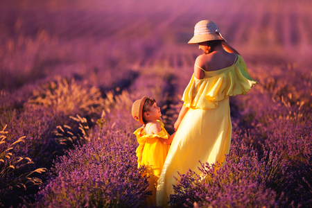 family. care for the younger ones. sisters with a doll in their hands in a lavender field. Closing bright lightの写真素材