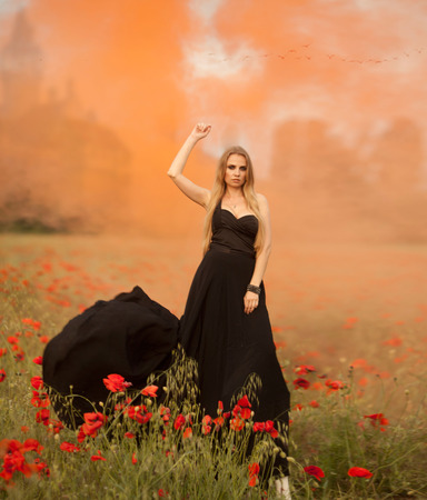 girl with a bouquet of poppies in black dressの写真素材