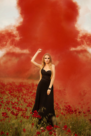girl with a bouquet of poppies in black dressの写真素材