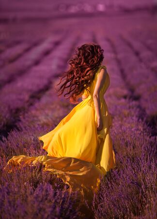 young girl in a beautiful dress walks in the field of lavenderの写真素材