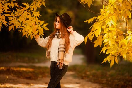 Attractive young woman in an autumnal shot outdoors. Beautiful fashionable school girl posing in park.の写真素材