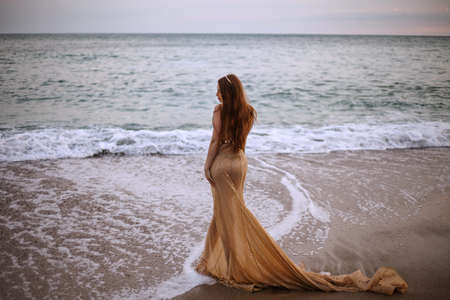 Young beautiful woman fallen angel stands on sea beach enjoy nature. costume bird white wings.の写真素材