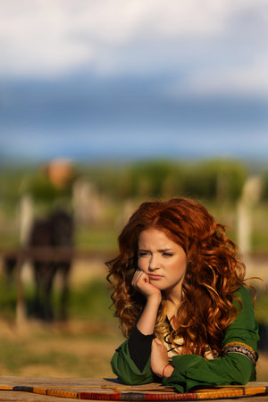 mysterious red-haired warrior girl stands. Lady elven princess holds bow and arrow.の写真素材