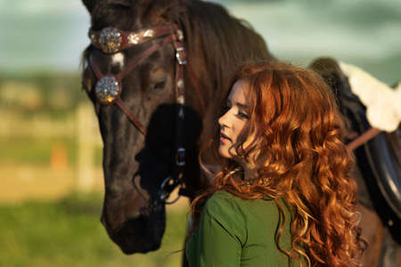 Medieval woman princess in green dress sits astride black steed horse.の写真素材