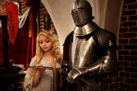 Beautiful blonde girl in medieval costume with a sword in her handsの写真素材