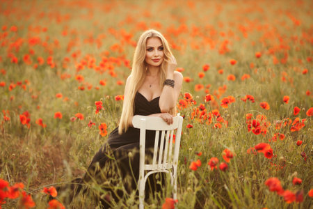 a girl in a black dress on a poppy field at sunset.の写真素材