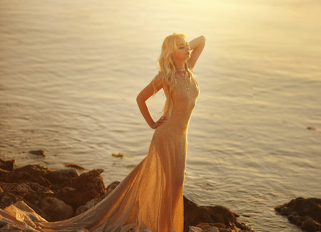 Beautiful girl in a long dress on the beach at sunset.の写真素材